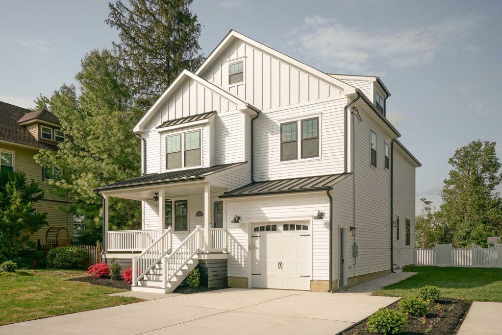 Outside of white, three story house with a patio