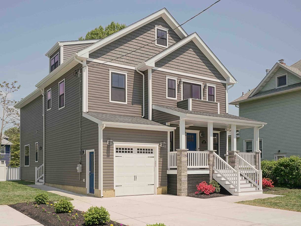 Outside view of beige, three story house with pateo, designed by Goldleaf Designs